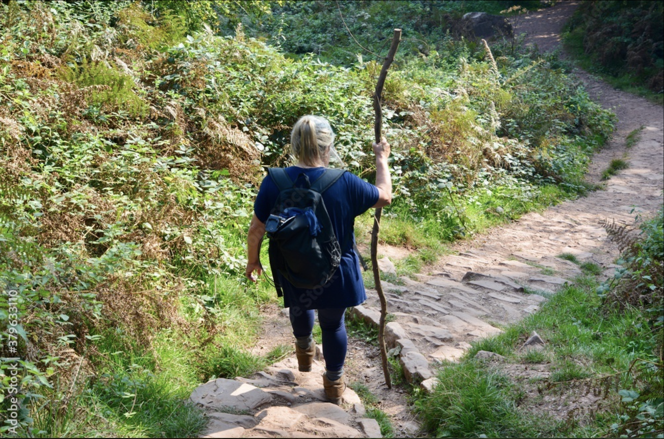 Female walker descending a woodland path near Abergavenny, Wales.